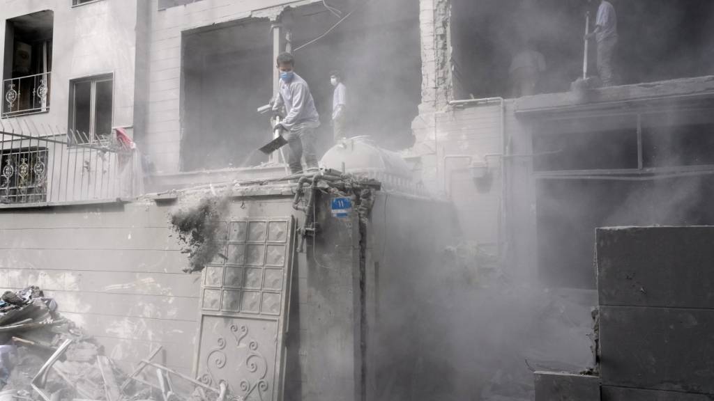 dpatopbilder - Freiwillige räumen in den Trümmer eines Wohnhauses, das beschädigt wurde, als eine nahe gelegene Polizeistation am Freitag bei einem amerikanisch-israelischen Angriff getroffen wurde, auf. Foto: Vahid Salemi/AP/dpa