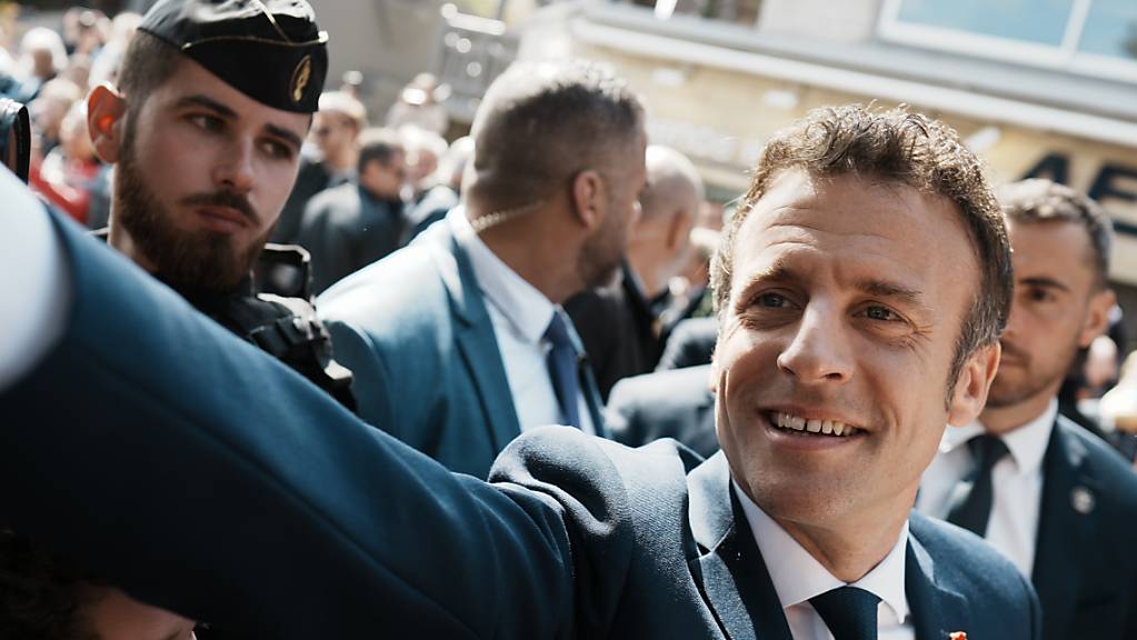 Emmanuel Macron, Präsident von Frankreich, schüttelt auf dem Weg zum Wahllokal die Hände von Gratulanten. Foto: Thibault Camus/AP/dpa