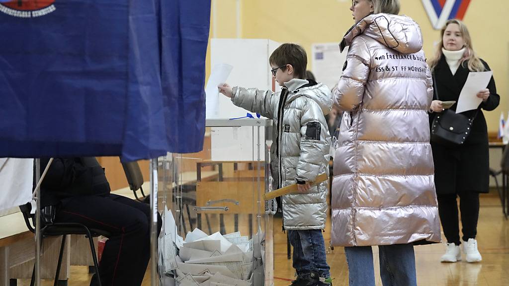 Menschen wählen in einem Wahllokal während der Präsidentschaftswahlen. Die Wähler in Russland gehen am letzten Tag der Präsidentschaftswahlen zu den Urnen. Foto: Dmitri Lovetsky/AP