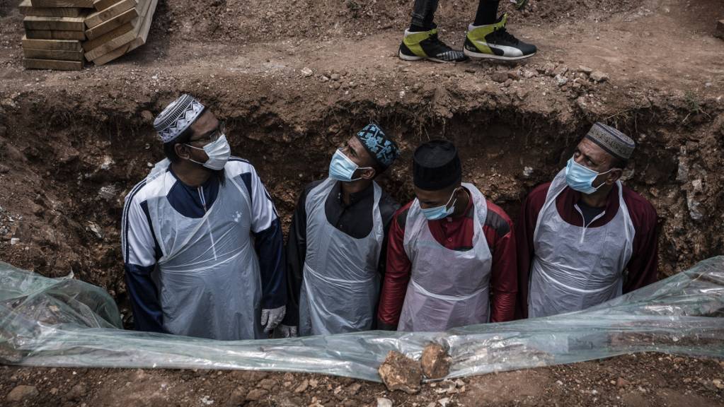 Bestatter in Schutzkleidung bereiten das Grab für eine an dem Coronavirus verstorbenen Person auf dem Avalon-Friedhof in Johannesburg für die Beerdigung vor. Foto: Shiraaz Mohamed/AP/dpa