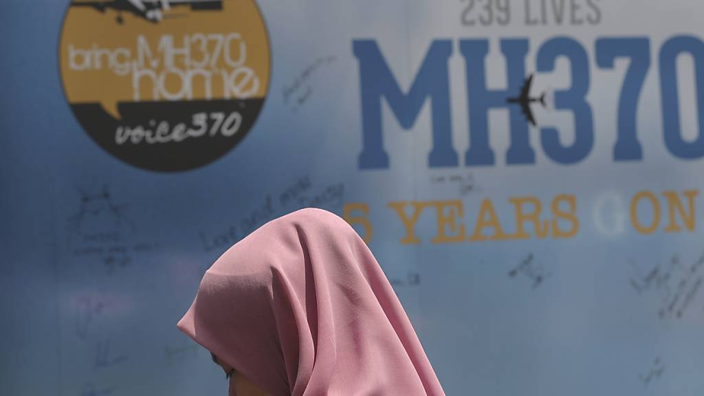 ARCHIV - Ein Mädchen steht während eines Gedenktages für das verschwundene Flugzeug MH370 vor einer Kondolenztafel. Foto: Vincent Thian/AP/dpa