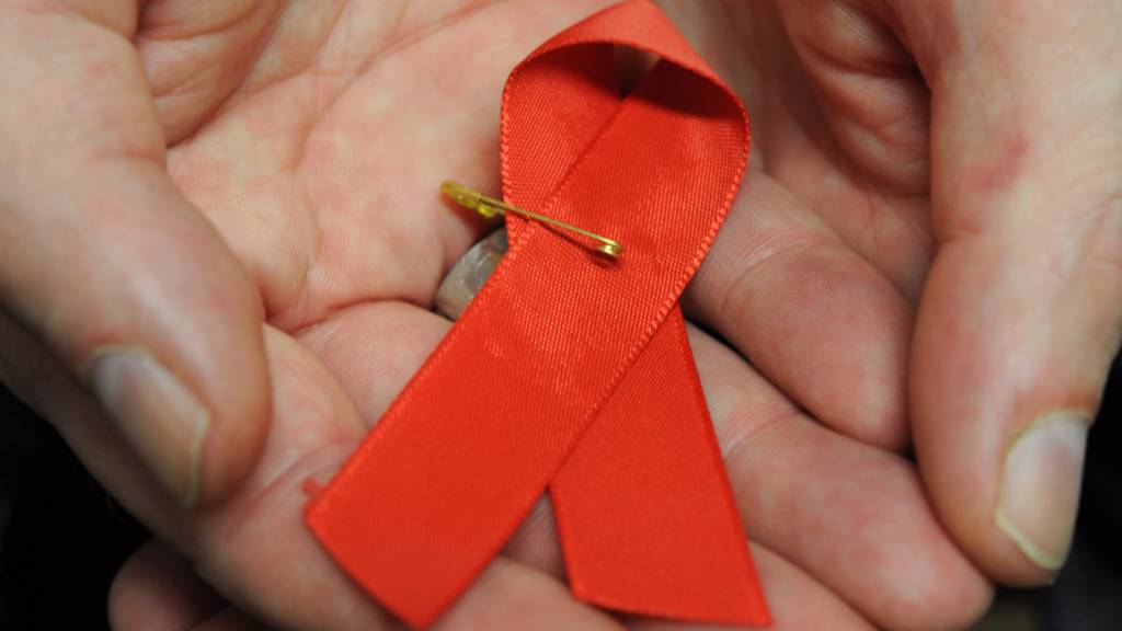 ARCHIV - Ein Mann hält eine rote Schleife als Symbol der Solidarität mit HIV-Positiven und Aids-Kranken. Foto: Arne Dedert/dpa