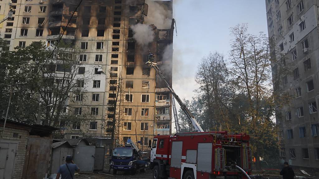 Feuerwehrleute löschen das Feuer nach dem Einschlag einer russischen Lenkbombe in einem Wohnhaus. Bei einem russischen Angriff auf die nordöstliche Stadt Charkiw mit starken Gleitbomben aus Flugzeugen wurden mehere Menschen getötet. Foto: Andrii Marienko/AP/dpa