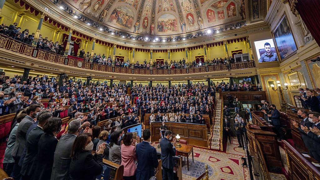 Parlamentarier hören Wolodymyr Selenskyj (r), Präsident der Ukraine, im Plenarsaal des spanischen Kongresses per Videoschalte zu. Selenskyj hat am Dienstag das Leiden der Menschen in seinem Land mit den Zerstörungen während des spanischen Bürgerkriegs verglichen. Foto: Manuu Fernandez/AP/dpa