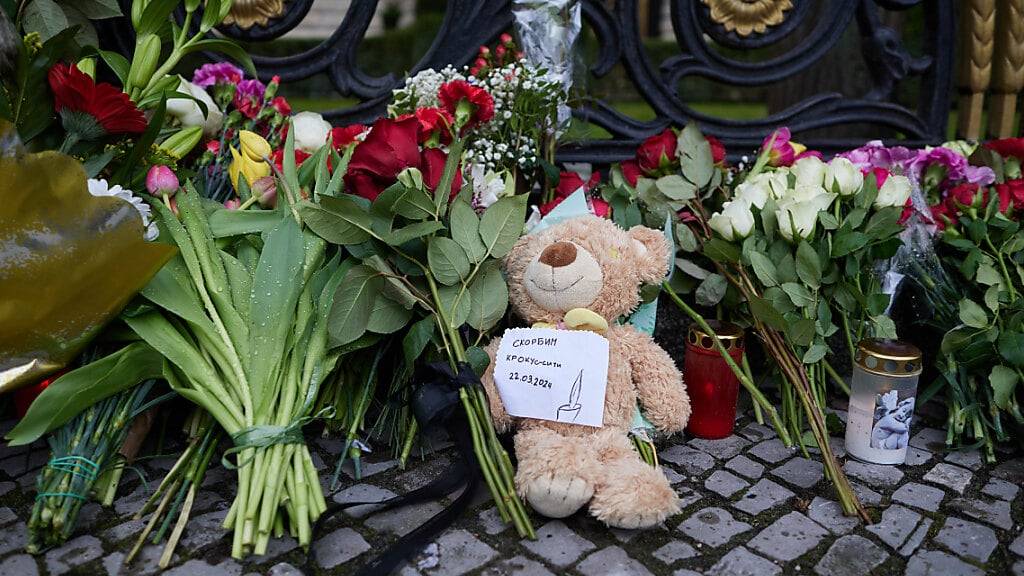 Blumen und ein Teddybär liegen am Zaun der russischen Botschaft in Berlin. Foto: Jörg Carstensen/dpa