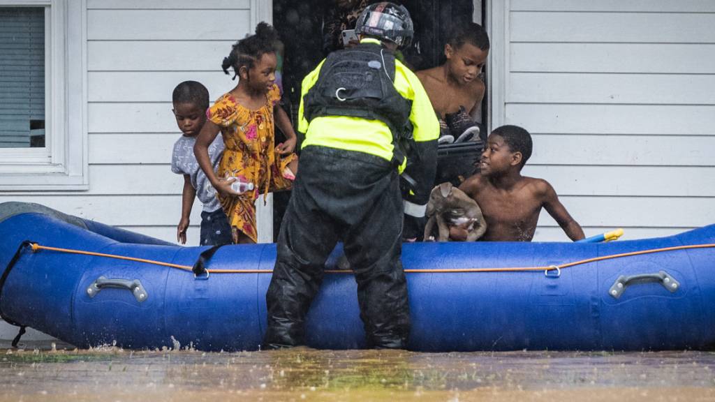 Ein Feuerwehrmann hilft Kindern beim Einstieg in ein Schlauchboot, da das Wohngebäude wegen des Hochwassers evakuiert werden muss. Der Tropensturm «Eta» zog mit starken Regenfällen über das Land hinweg. Foto: Andrew Dye/The Winston-Salem Journal/AP/dpa