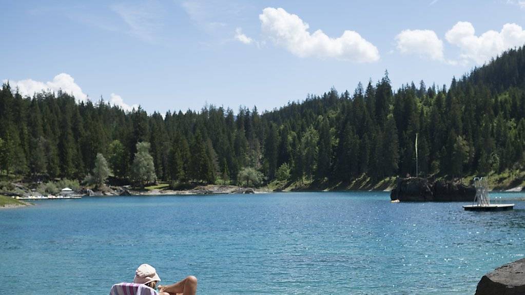 Eine Frau sitzt bei warmen Temperaturen am Caumasee in Flims. Im Juli haben Inländer vermehrt Ferien in der Schweiz gemacht.