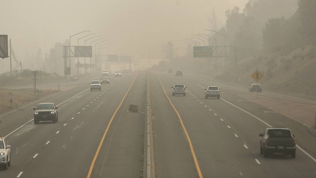 Autos fahren auf der Golden Center Autobahn durch dichten Rauch, der sich von den Waldbränden an der Westküste der USA ausbreitet.