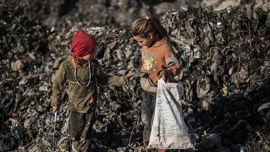 Zwei Kinder suchen auf einer Mülldeponie nach wiederverwertbaren Abfällen wie Plastik und Altmetall.