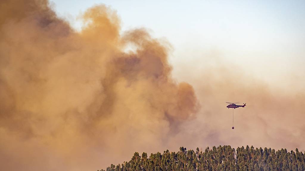 Ein Hubschrauber über den Rauchschwaden eines  Waldbrandes in der Gemeinde Almonaster la Real. Foto: A. Perez/Europa Press/AP/dpa