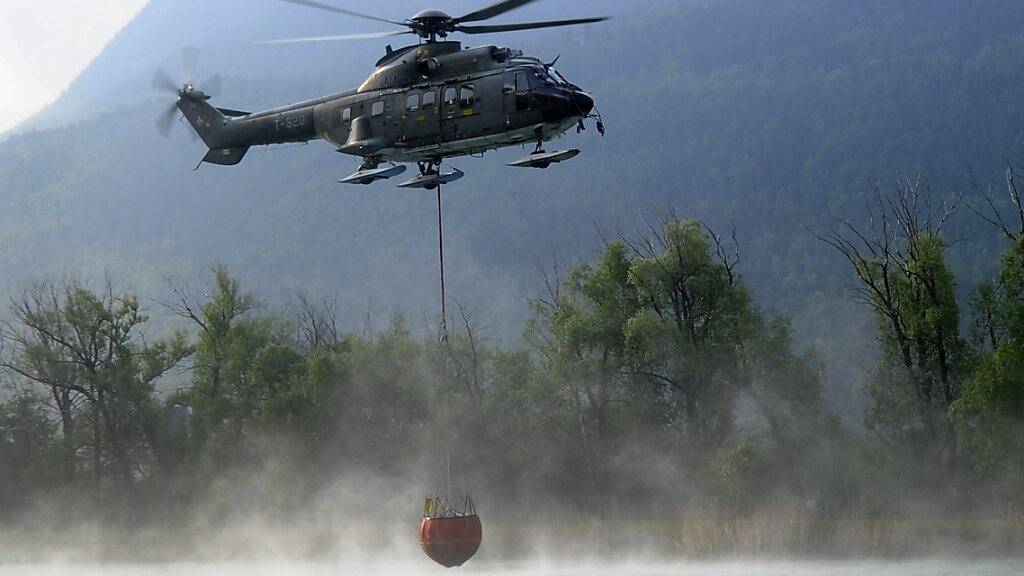 Ein Superpuma der Schweizer Armee nimmt im April dieses Jahres nahe Visp VS Wasser für eine Brandbekämpfung auf. (Archivbild)