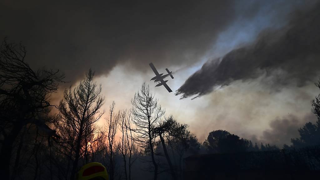 Ein Flugzeug wirft über einem Waldbrand nördlich von Athen Löschwasser ab. Foto: Michael Varaklas/AP/dpa