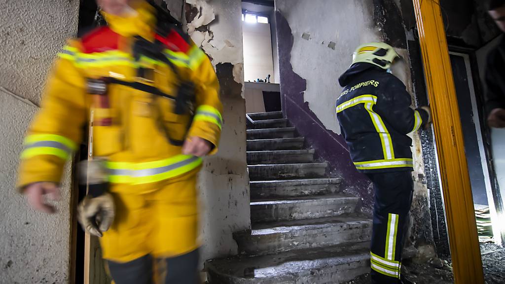 Feuerwehrleute an der Arbeit im vom Brand beschädigten Wohnblock in Genf.
