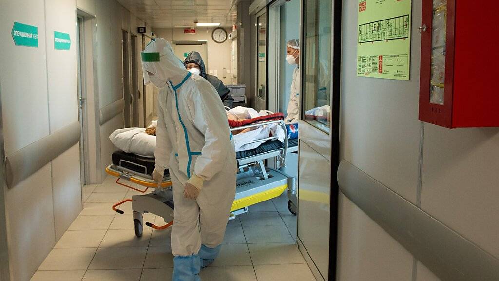 ARCHIV - Medizinische Mitarbeiter in Schutzkleidung schieben das Bett eines Corona-Patienten im städtischen Krankenhaus Nr. 52 in Moskau. (Archivbild) Foto: Denis Grishkin/Moscow News Agency/AP/dpa