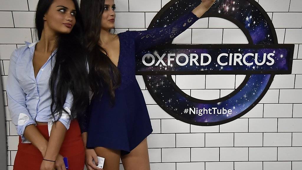 Neben einen Zug: Zwei Nachtschwärmerinnen in London nutzen die U-Bahn, die neuerdings an Wochenenden rund um die Uhr fährt.