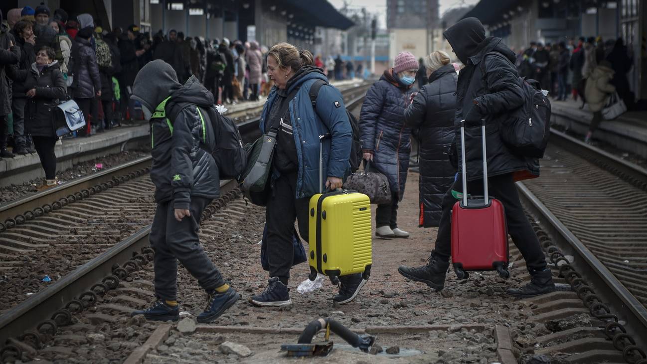 Menschen überqueren die Gleise im Hauptbahnhof Kiews, um aus der Ukraine zu fliehen.