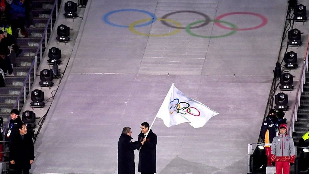 IOC-Präsident Thomas Bach übergibt im Rahmen der Schlussfeier in Pyeongchang die Olympische Flagge an Pekings Stadtpräsidenten Chen Jining.