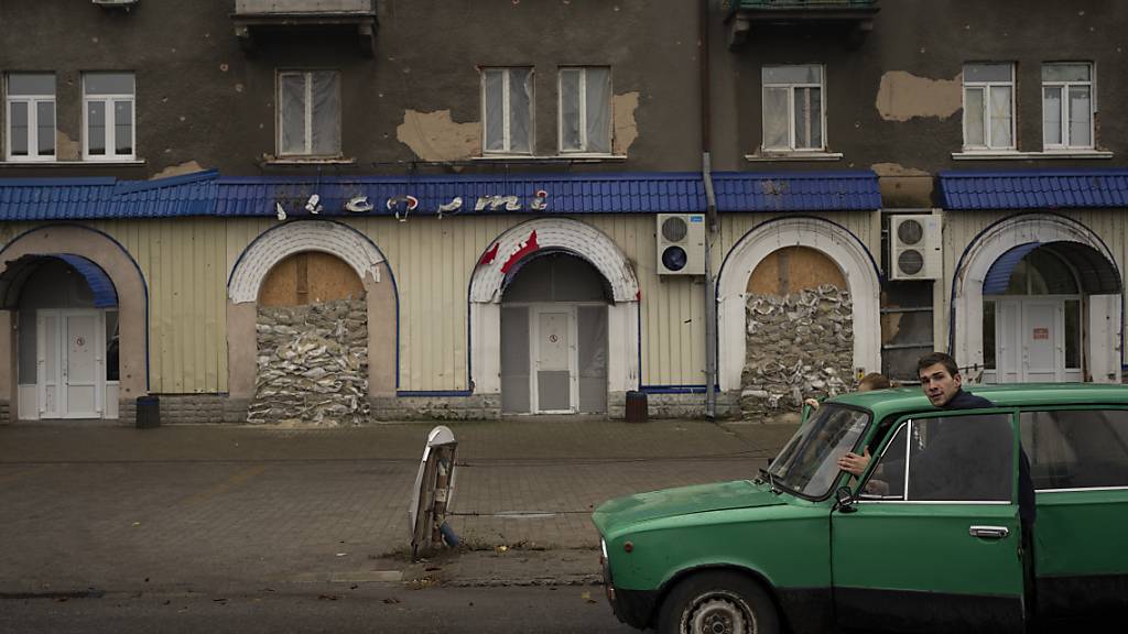 Menschen schieben ein liegengebliebenes Fahrzeug an einem stillgelegten Restaurant vorbei. Foto: Bram Janssen/AP/dpa