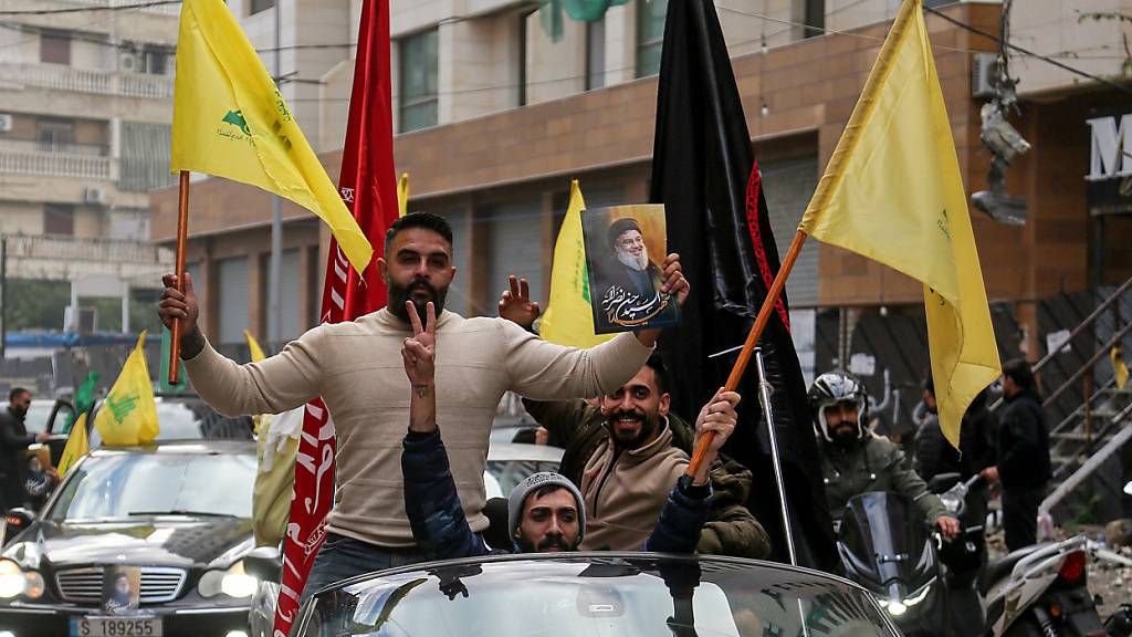 Bewohner der südlichen Vorstadt von Beirut schwenken die Fahnen der pro-iranischen Hisbollah, als sie jubelnd in die zerstörte Parteihochburg zurückkehren. Foto: Marwan Naamani/dpa