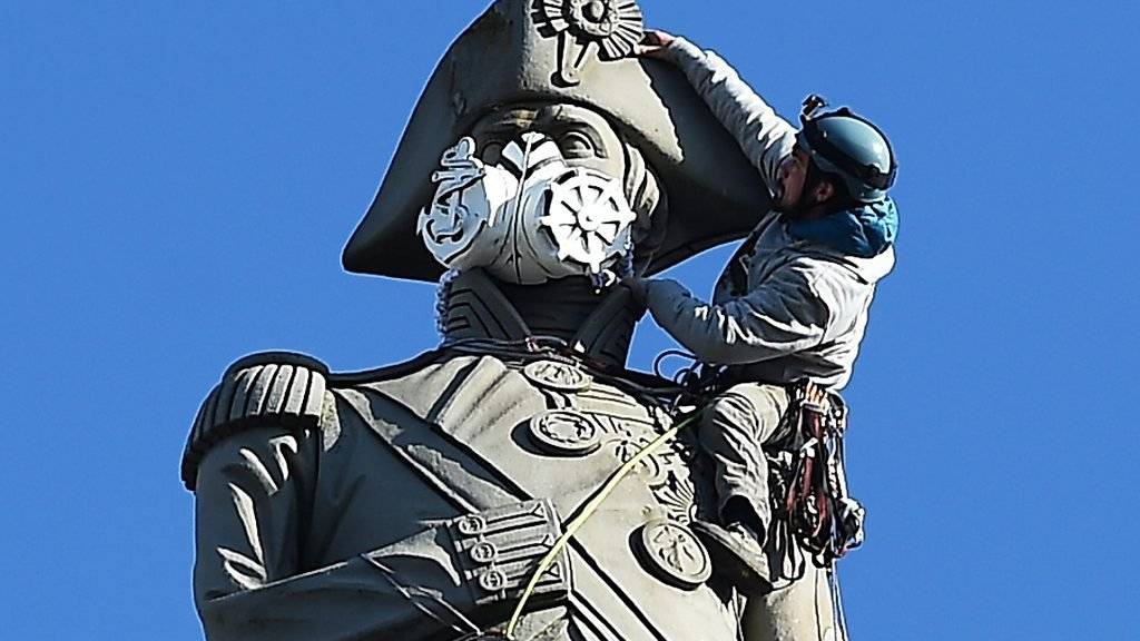 Ein Greenpeace-Aktivist setzt der Statue von Admiral Nelson am Londoner Trafalgar Square eine Gasmaske auf.