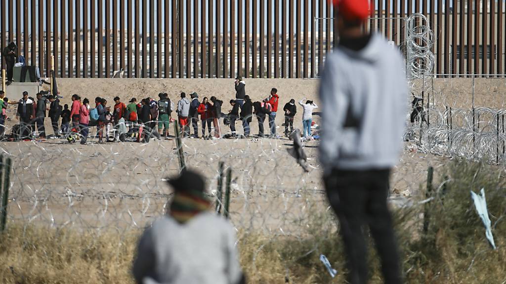 Migranten stellen sich an der US-Grenzmauer auf, nachdem sie von den US-Einwanderungsbehörden festgehalten wurden. Bewaffnete haben im Nordosten von Mexiko an der Grenze zu den USA 31 Migranten aus einem Bus entführt. Foto: Christian Chavez/AP