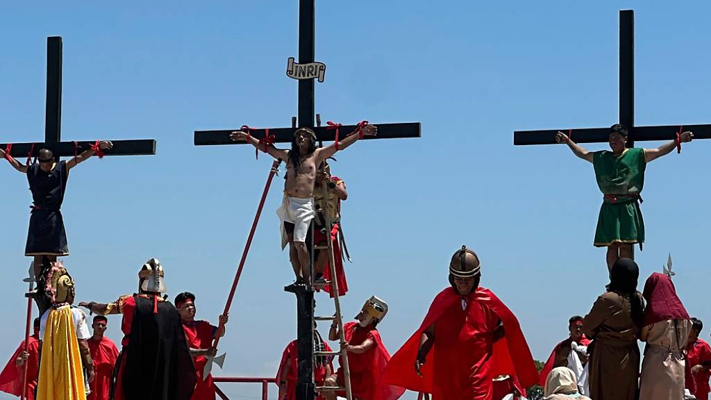 Drei philippinische Gläubige hängen während der Darstellung der Kreuzigung von Jesus Christus an drei Holzkreuzen. Foto: Joeal Calupitan/AP/dpa
