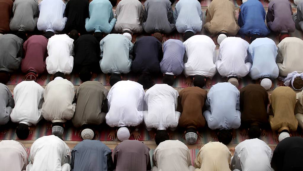 Betende Menschen knien im Innern einer Moschee. (Symbolbild)