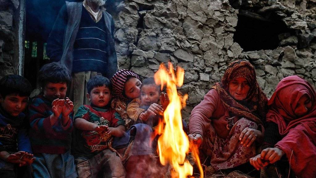 Überlebende des Erdbebens wärmen sich im pakistanischen Chitral-Tal an einem Feuer