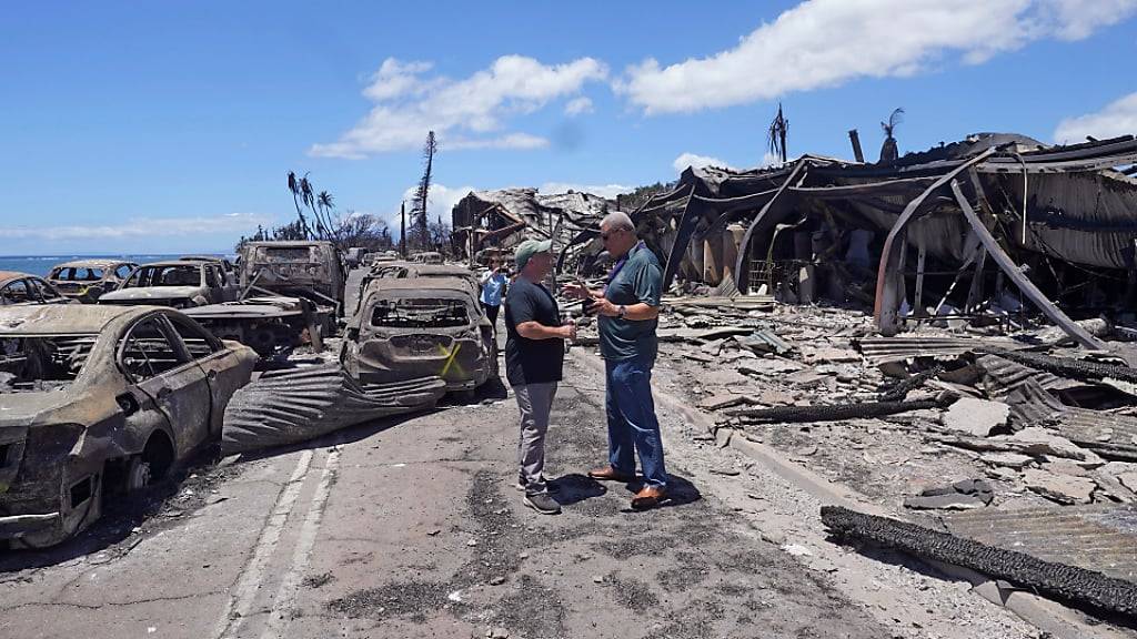 Josh Green (l), Gouverneur von Hawaii, und Richard Bissen Jr., Bürgermeister von Maui County, sprechen während einer Besichtigung der Waldbrandschäden in Lahaina, Hawaii. Foto: Rick Bowmer/AP/dpa
