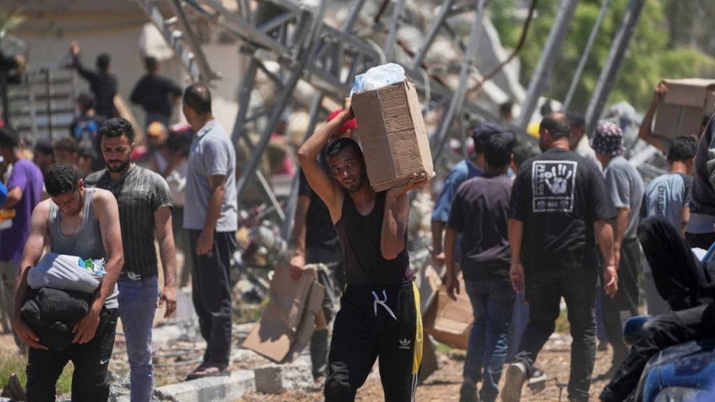 Palästinenser tragen Kisten und Taschen mit Lebensmitteln und humanitären Hilfspaketen, die von der Gaza Humanitarian Foundation, einer von Israel anerkannten und von den USA unterstützten Organisation, in Khan Younis im südlichen Gazastreifen geliefert wurden. Foto: Abdel Kareem Hana/AP/dpa