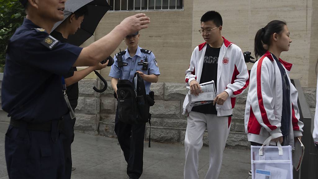 Ein Polizeibeamter kontrolliert die Tasche eines Schülers, der zur jährlichen nationalen Hochschulaufnahmeprüfung in Peking ankommt. Foto: Ng Han Guan/AP/dpa