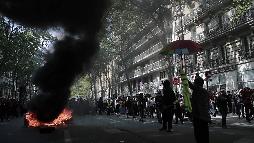 Demonstranten stehen neben brennendem Müll und Materialien, die während eines Demonstrationszuges in Paris zum 1. Mai angezündet wurden. Foto: Lewis Joly/AP/dpa