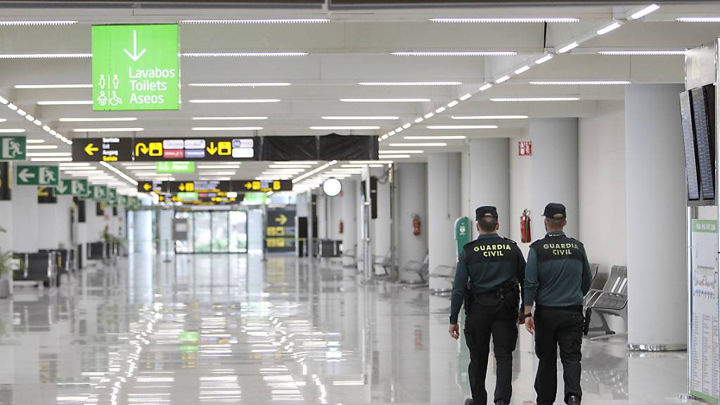 Zwei Zivilbeamte patrouillieren am Flughafen Palma de Mallorca. Wegen wieder anziehender Corona-Zahlen hat die Regionalregierung Mallorcas die Maßnahmen gegen die Ausbreitung des Coronavirus über Weihnachten verschärft. Foto: Isaac Buj/EUROPA PRESS/dpa