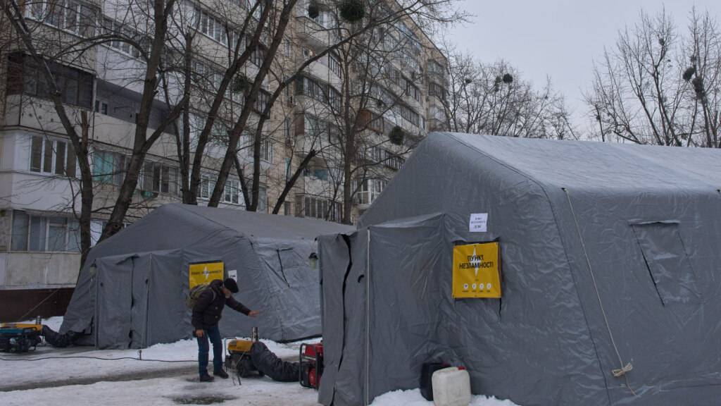 ARCHIV - Ein Mann wärmt sich in einem Zelt auf, in denen sich die Menschen aufwärmen können, nach den russischen Luftangriffen auf den ukrainischen Energiesektor. Ein Teil der Bewohner der Stadt sind mitten im Winter ohne Strom, Wasser und Heizung. Foto: Efrem Lukatsky/AP/dpa