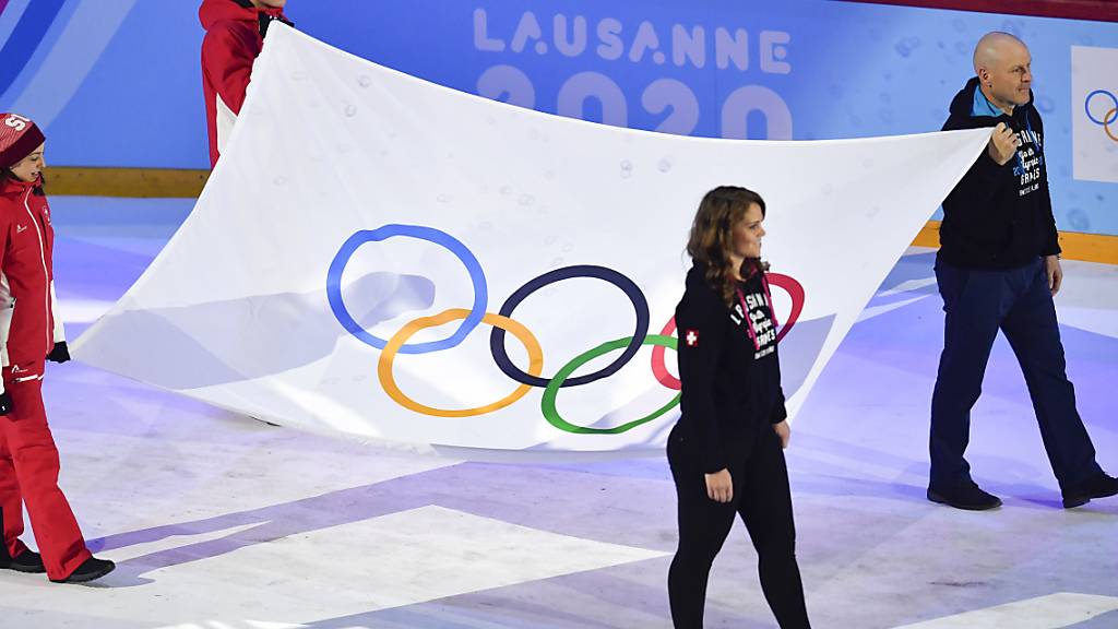 Die Olympische Fahne in der Eisarena Malley, gezogen von Diidier Cuche und Florence Schilling