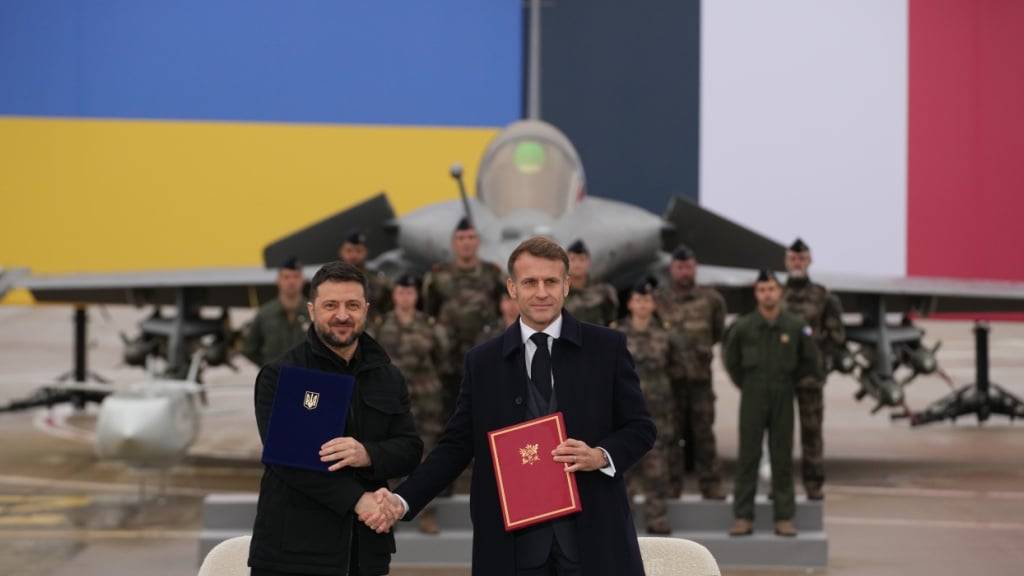 Der französische Präsident Emmanuel Macron (r) und der ukrainische Präsident Wolodymyr Selenskyj schütteln sich nach der Unterzeichnung eines Abkommens auf dem Luftwaffenstützpunkt Villacoublay bei Paris die Hände. Foto: Christophe Ena/Pool AP/dpa