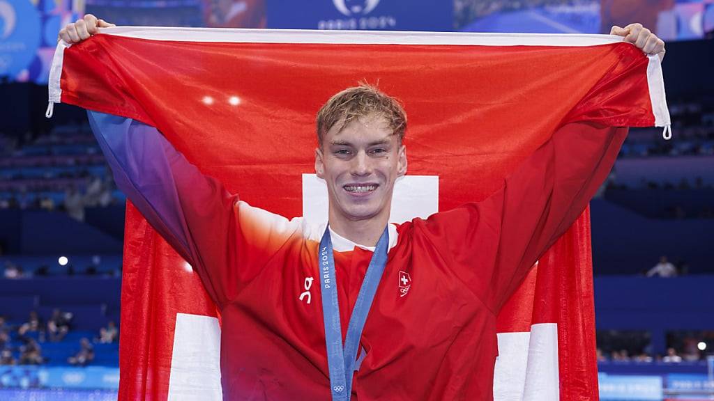 Roman Mityukov posiert nach dem Gewinn der Bronzemedaille mit der Schweizer Flagge