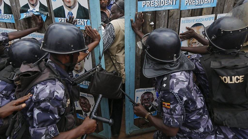 Polizisten versuchen das Tor des Parteisitzes von Oppositionskandidat Besigye zu schliessen.