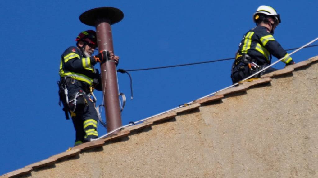 dpatopbilder - Feuerwehrleute platzieren den Schornstein auf dem Dach der Sixtinischen Kapelle, wo sich die Kardinäle zur Wahl des neuen Papstes versammeln werden. Foto: Gregorio Borgia/AP/dpa