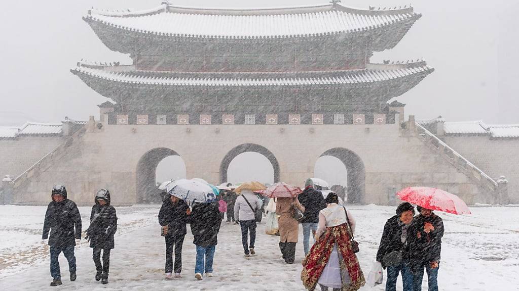 Touristen gehen bei Schneefall am Gyeongbokgung-Palast. Foto: Kim Jae-Hwan/SOPA Images via ZUMA Press Wire/dpa