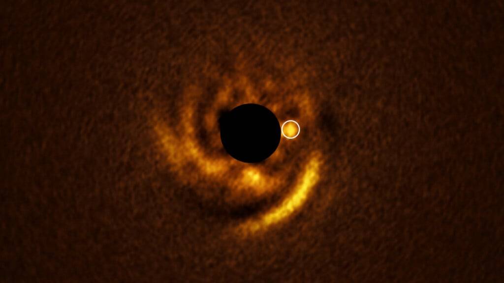 Dieses Bild, aufgenommen mit dem Very Large Telescope (VLT) der ESO, zeigt eine spiralförmige Scheibe um den jungen Stern HD 135344B. Der schwarze Kreis in der Mitte stammt von einem Koronagraphen – einem Gerät, das das Licht des Sterns blockiert, um schwache Details um ihn herum sichtbar zu machen.