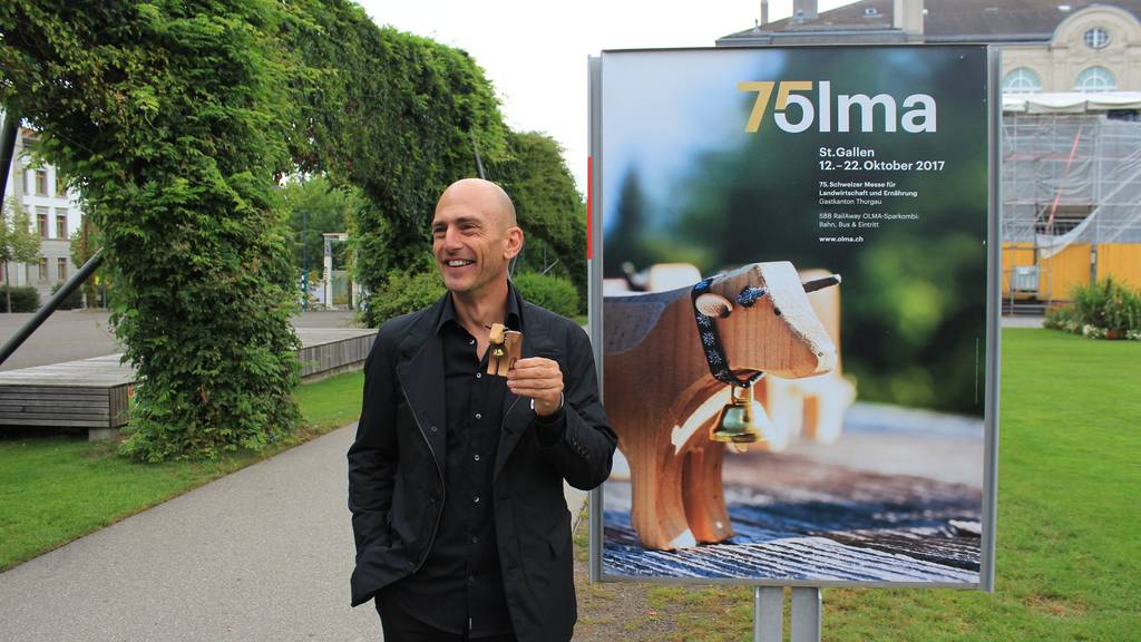 Andreas Tschachtli und die Spielzeug-Kuh seiner Tochter vor dem aktuellen Olma-Plakat. (Bild: zVg)