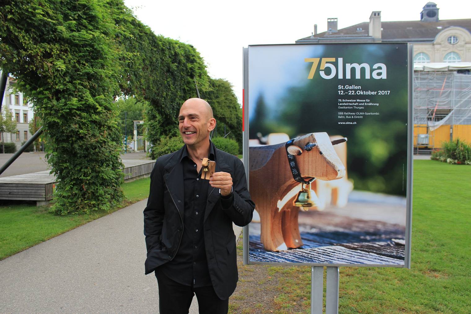 Andreas Tschachtli und die Spielzeug-Kuh seiner Tochter vor dem aktuellen Olma-Plakat. (Bild: zVg)