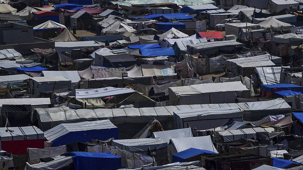 ARCHIV - Palästinenser, die durch die israelische Luft- und Bodenoffensive im Gazastreifen vertrieben wurden, gehen durch ein behelfsmäßiges Zeltlager. Foto: Abdel Kareem Hana/AP/dpa