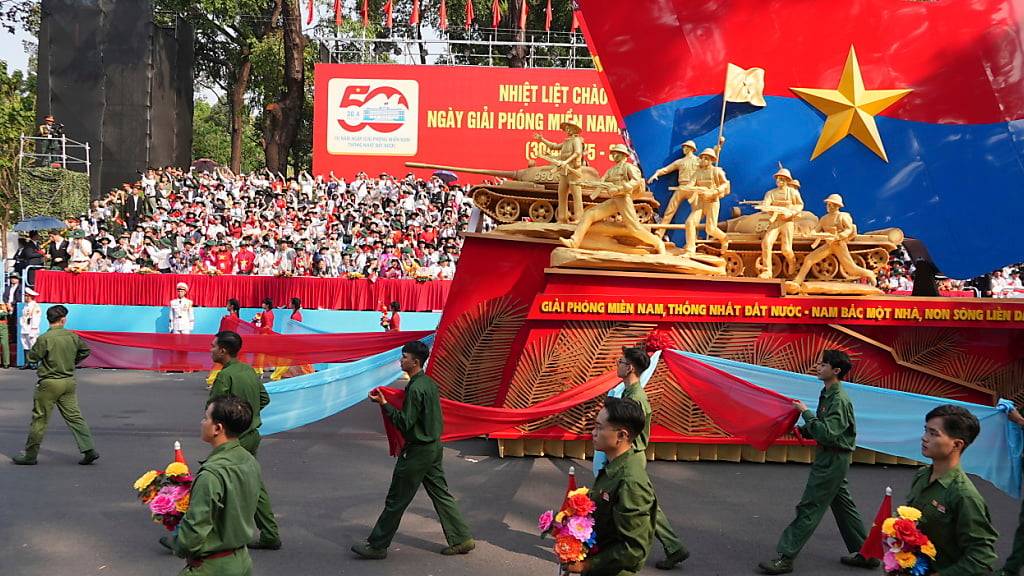 Ein Wagen mit einer Struktur zum Gedenken an den 50. Jahrestag des Endes des Vietnamkriegs wird während einer Parade bewegt. Foto: Hau Dinh/AP/dpa