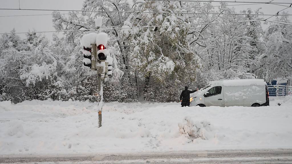Ein Mann räumt Schnee von der Windschutzscheibe seines Fahrzeugs. Schnee und Eis haben im Süden Bayerns auf den Straßen und bei der Bahn für Chaos gesorgt. Foto: Lukas Barth/dpa