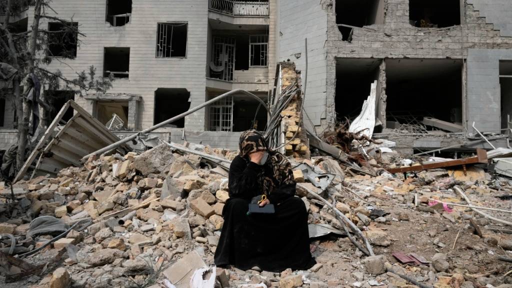 Eine Frau sitzt auf den Trümmern eines Wohnhauses, das am vergangenen Montag während der amerikanisch-israelischen Luftangriffe beschädigt wurde. Foto: Vahid Salemi/AP/dpa