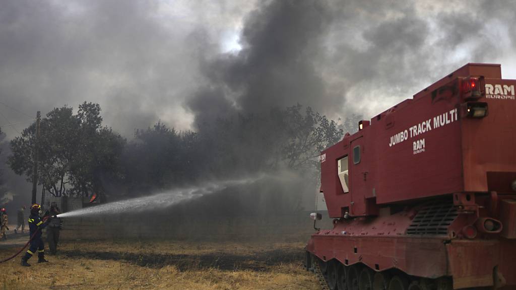dpatopbilder - Feuerwehrleute versuchen mit Hilfe eines umgebauten Leopard-Panzers den Waldbrand neben dem christlich-orthodoxen Kloster Agia Paraskevi unter Kontrolle zu bringen. Das Spezialfahrzeug verfügt über eine  Kapazität für 15.000 Liter Löschwasser, einer Schaufel für unwegsames Gelände und einer Rettungskammer für zehn Menschen. Foto: Thanassis Stavrakis/AP/dpa