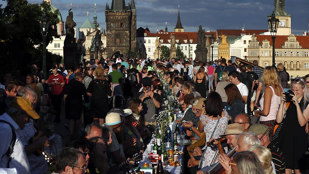 dpatopbilder - Anwohner sitzen zum Essen an einem 500 Meter langen Tisch auf der mittelalterlichen Karlsbrücke, nachdem die Einschränkungen während der Corona-Pandemie gelockert wurden. Foto: Petr David Josek/AP/dpa