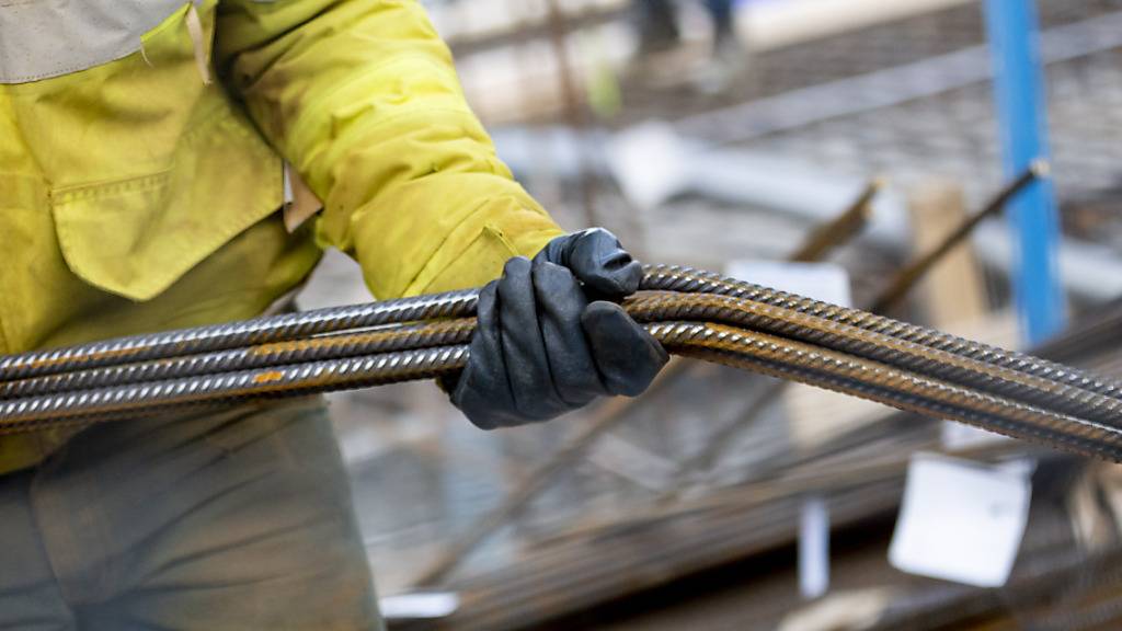 Ein Bauarbeiter trägt auf einer Baustelle nahe des Alexanderplatzes Stahlstangen. Die Stimmung der Unternehmen im Euro-Raum ist im September überraschend auf ein langjähriges Tief gefallen. (Symbolbild)